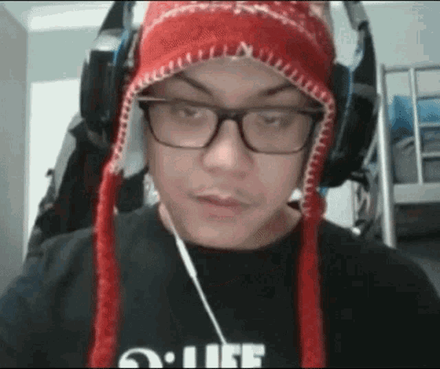 a man wearing a red hat and headphones is wearing a black shirt with the word life on it