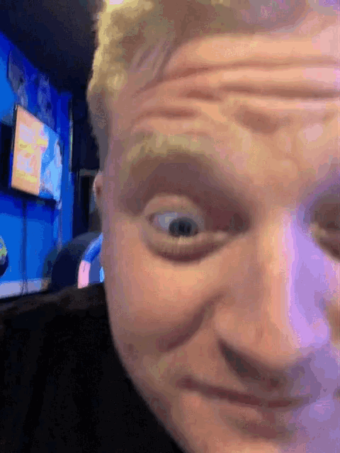 a close up of a man 's face with a tv on the wall behind him