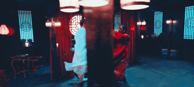 a woman in a red dress is holding a sword and looking at a man .