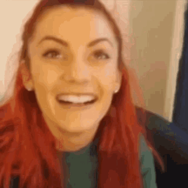 a close up of a woman 's face with red hair smiling .