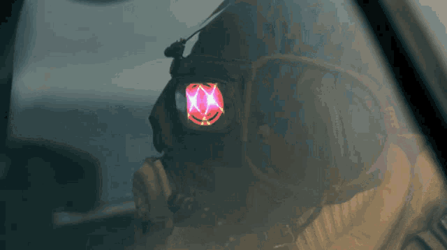 a close up of a person wearing a gas mask with a red light coming out of their eyes