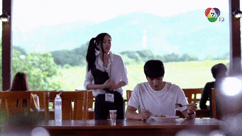 a man is sitting at a table with a woman standing behind him .