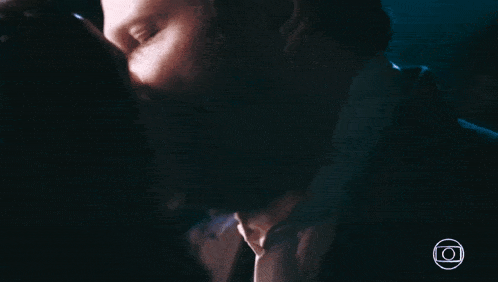 a man and woman are kissing in a dark room