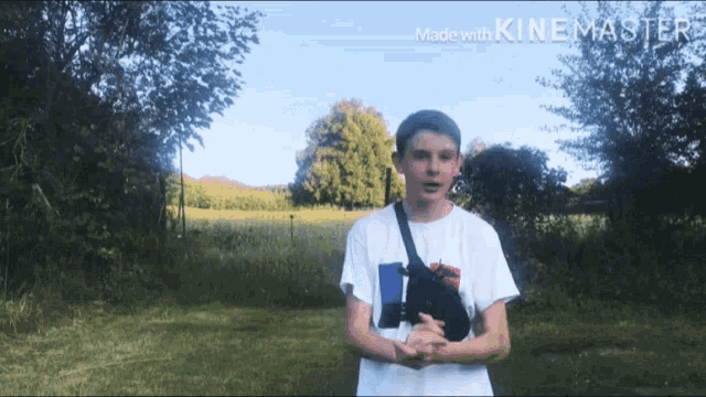 a boy in a white shirt is standing in a field with trees in the background and the words made with kinemaster at the top