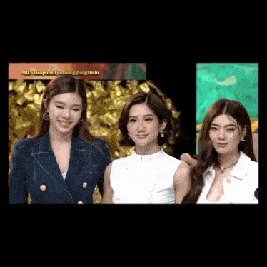 three women standing next to each other in front of a sign that says ' a '
