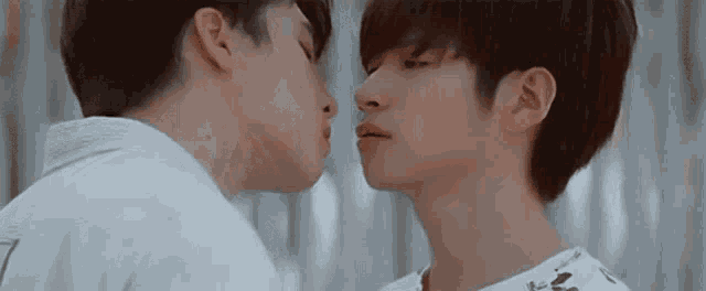 a couple of young men are kissing each other on the cheek .