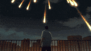 a man stands on a balcony watching fireworks falling from the sky