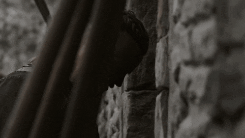 a woman leaning against a stone wall with her head resting on a railing