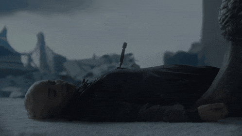 a woman is laying on the ground with a sword in her chest