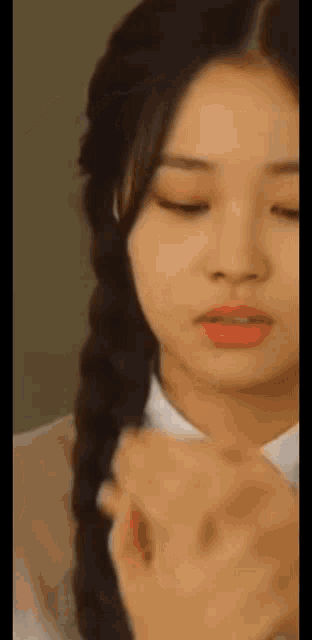 a close up of a woman 's face with her eyes closed and a braid in her hair .