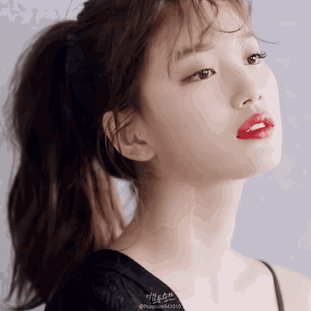 a close up of a woman with a ponytail and red lipstick
