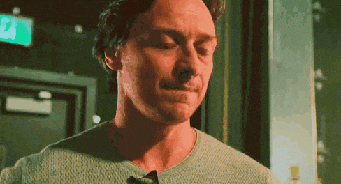 a close up of a man 's face with his eyes closed and a green exit sign behind him .