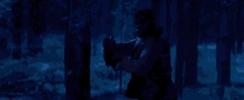 a person is holding a red light saber in the snow in a forest .