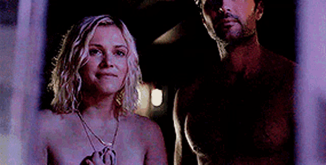 a man and a woman without shirts are standing next to each other in a dark room .