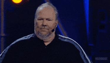 a man in a black shirt is standing on a stage with blue lights