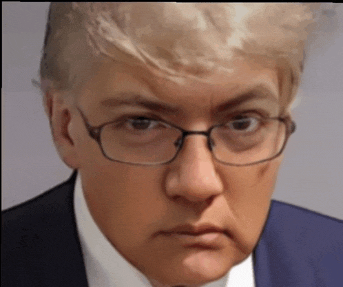 a man wearing glasses and a suit looks angry