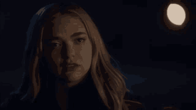 a close up of a woman 's face in the dark with a light in the background .