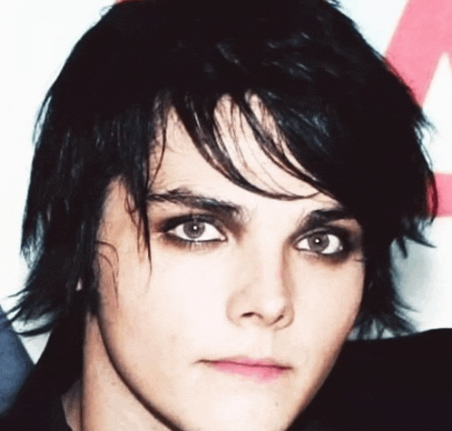 a close up of a young man 's face with black hair and green eyes