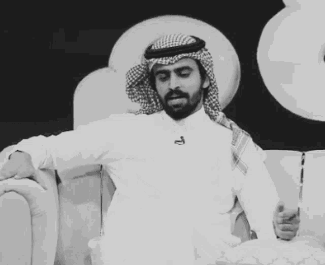 a man with a beard wearing a head scarf and a white shirt