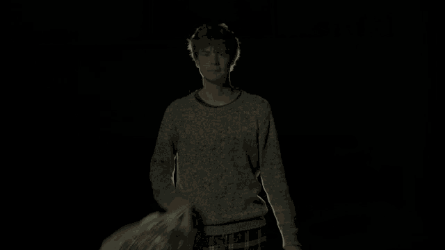 a man in a grey sweater is holding a green bag with a green leaf on it