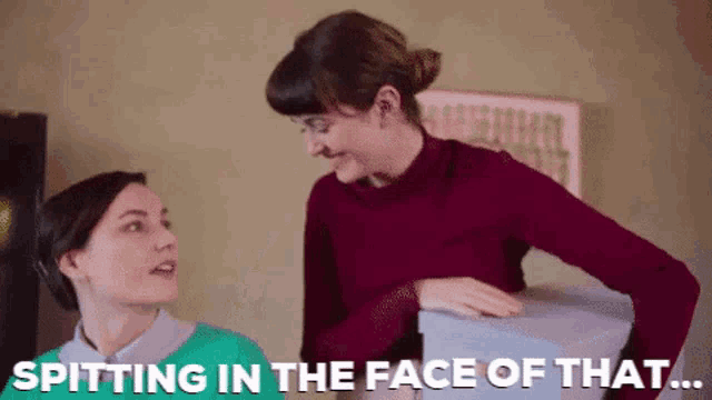 a woman is spitting in the face of another woman while holding a box