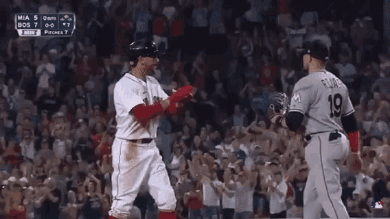 two baseball players are standing next to each other on a field .