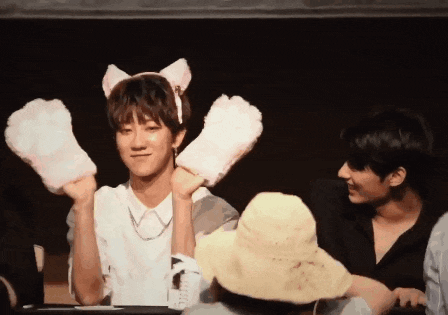 a boy wearing a cat ear headband is holding a pair of paws in his hands .
