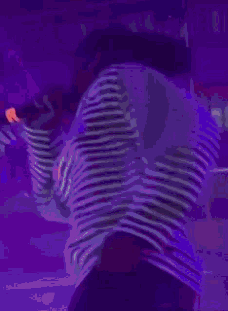 a person in a striped shirt stands in a dark room