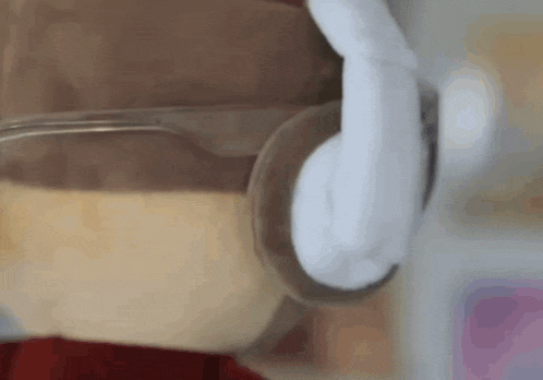 a close up of a person holding a glass of coffee with headphones on .