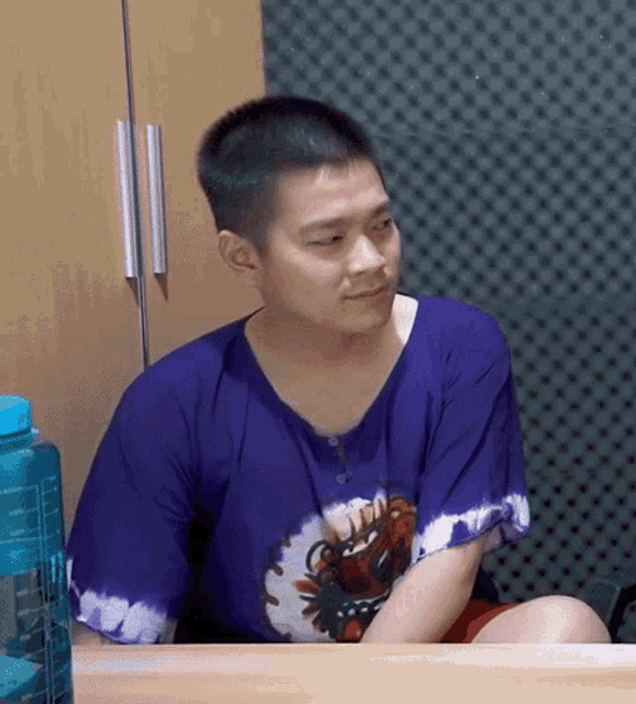 a man wearing a purple shirt with a dragon on it