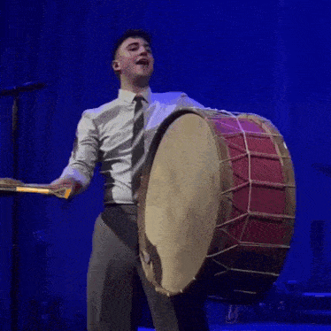 a man in a white shirt and tie is playing a drum