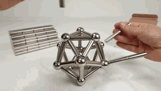 a person is holding a piece of metal that looks like a pyramid