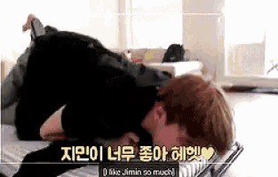 a man is laying on his stomach on a bed and says i like jimin so much in korean .