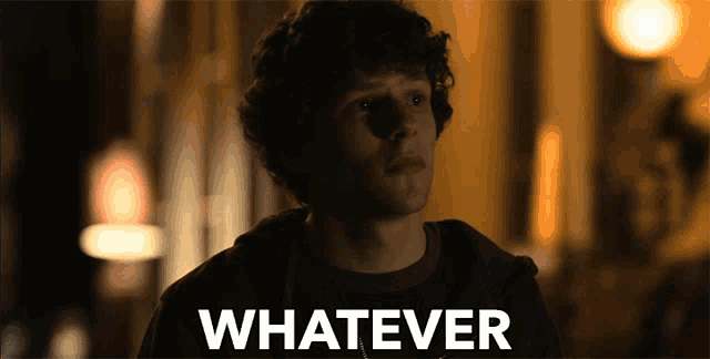 a man with curly hair stands in front of a sign that says " whatever "