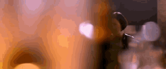 a close up of a person 's face with a blurry background and a heart shaped object in the foreground .