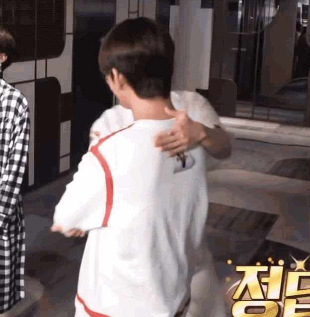 a man in a white shirt is hugging another man in a black and white checkered shirt