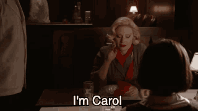 a woman sitting at a table with the words i 'm carol on the bottom
