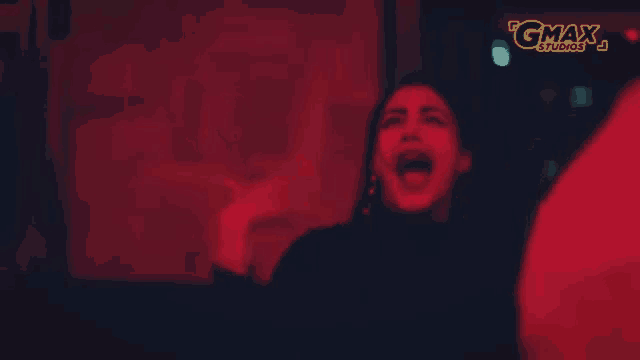a woman is screaming in front of a sign that says gmax studios .