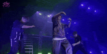 a man is dancing on a stage in front of a screen that says ' x ' on it .