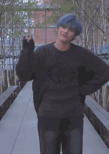 a man with blue hair wearing a black sweater and jeans