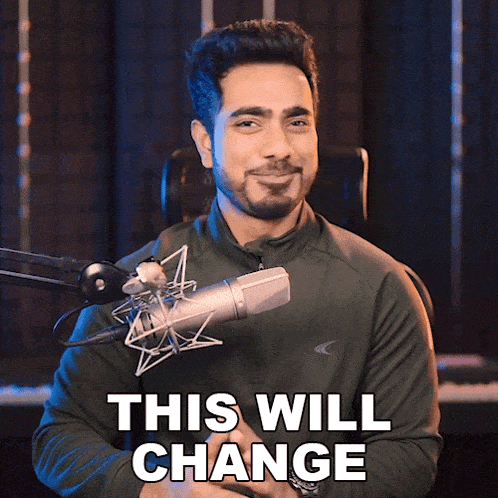 a man standing in front of a microphone with the words " this will change " above him