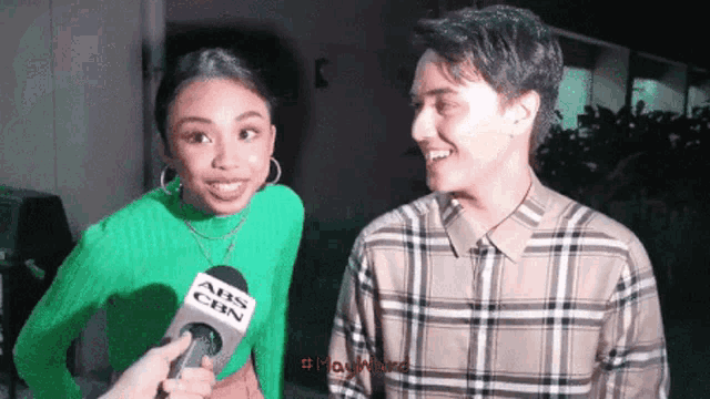 a man in a plaid shirt is being interviewed by a woman wearing a green sweater