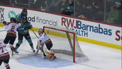 a hockey game is being played in front of a rwbarnabas ad