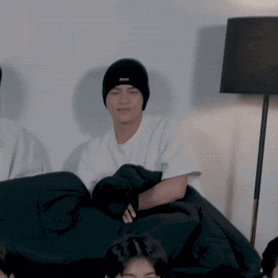 a man wearing a black beanie with the word abercrombie on it sits next to a lamp