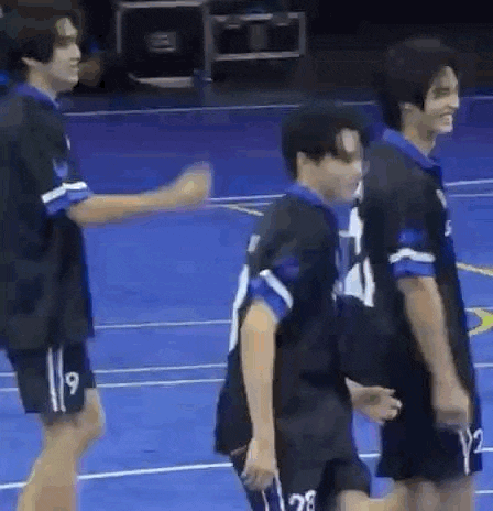 a group of young men are standing next to each other on a blue court .