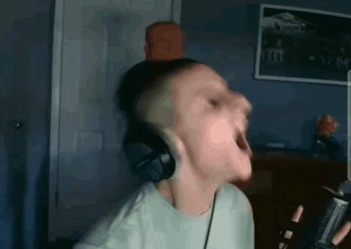a man wearing headphones is singing into a microphone while holding a remote control .