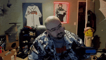 a man in a room with a picture of a braves jersey on the wall behind him