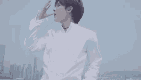 a man in a white shirt and choker is standing in front of a city .