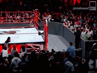a wrestling match is going on in front of a crowd .