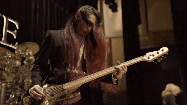 a man with long red hair is playing a purple guitar